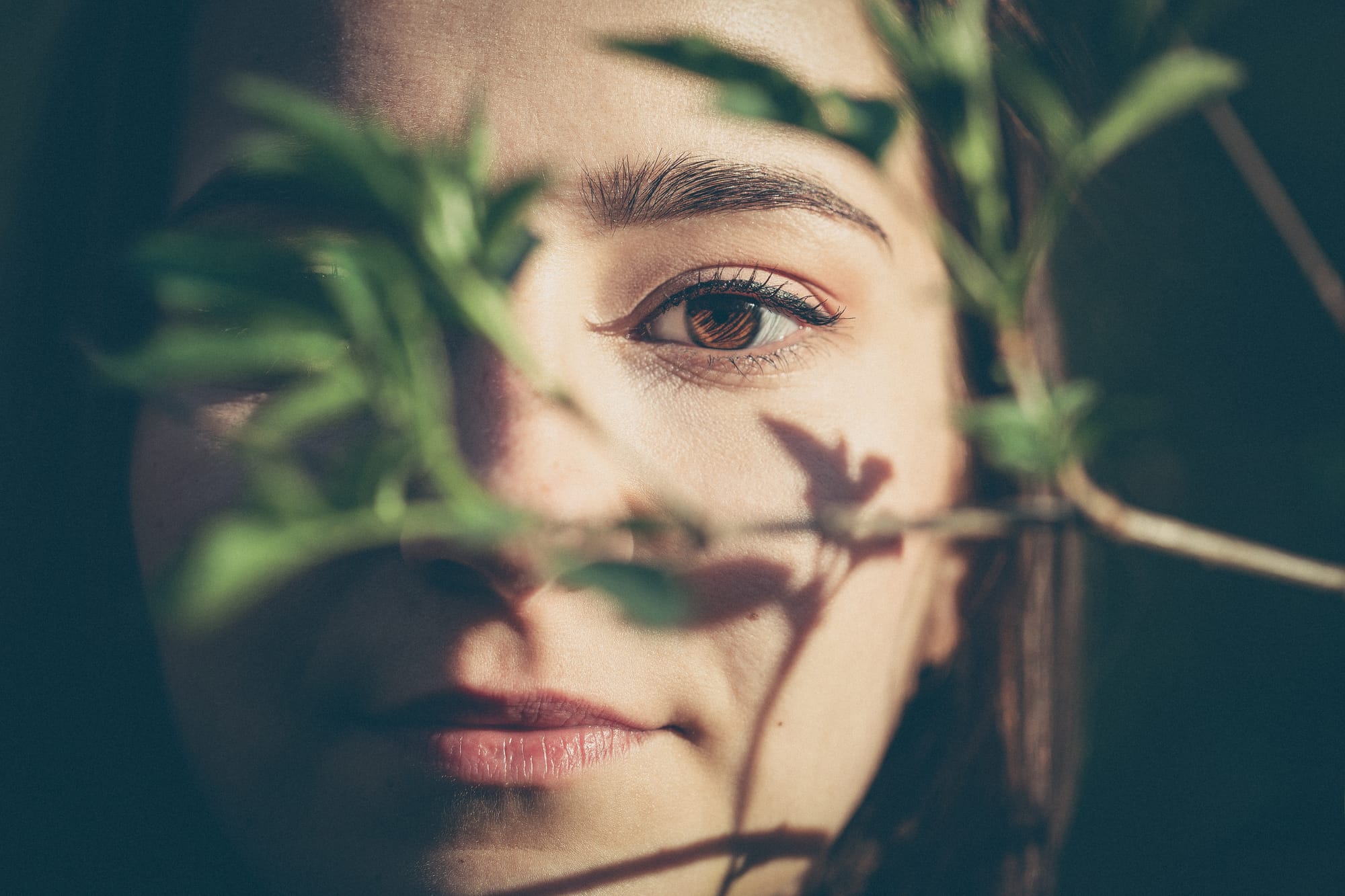 Girl looking into the camera behind tree branches